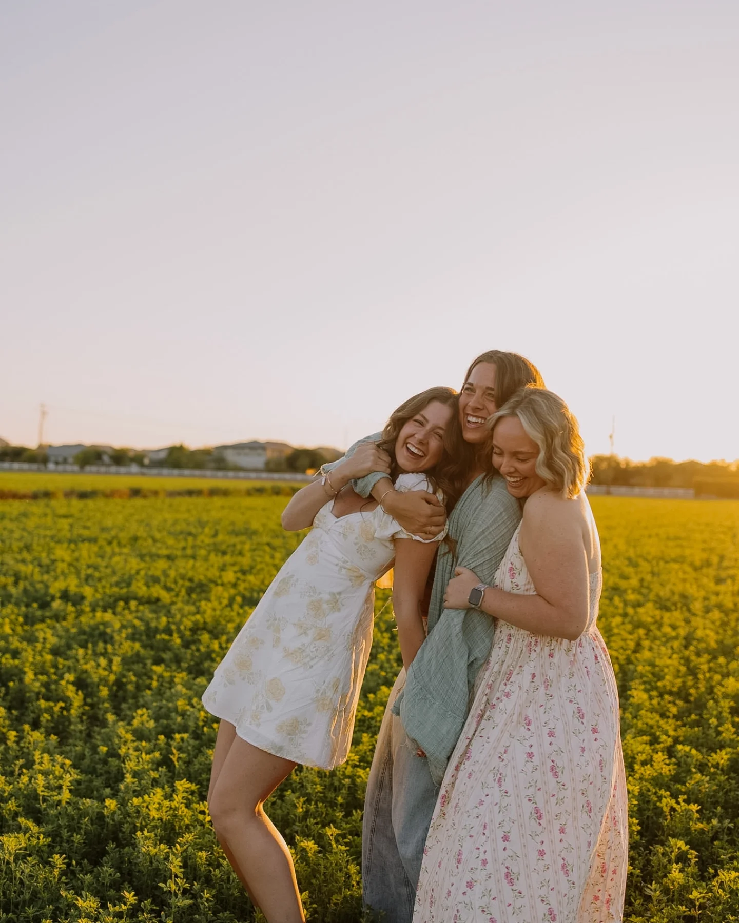 Three women laughing together in a flower field
