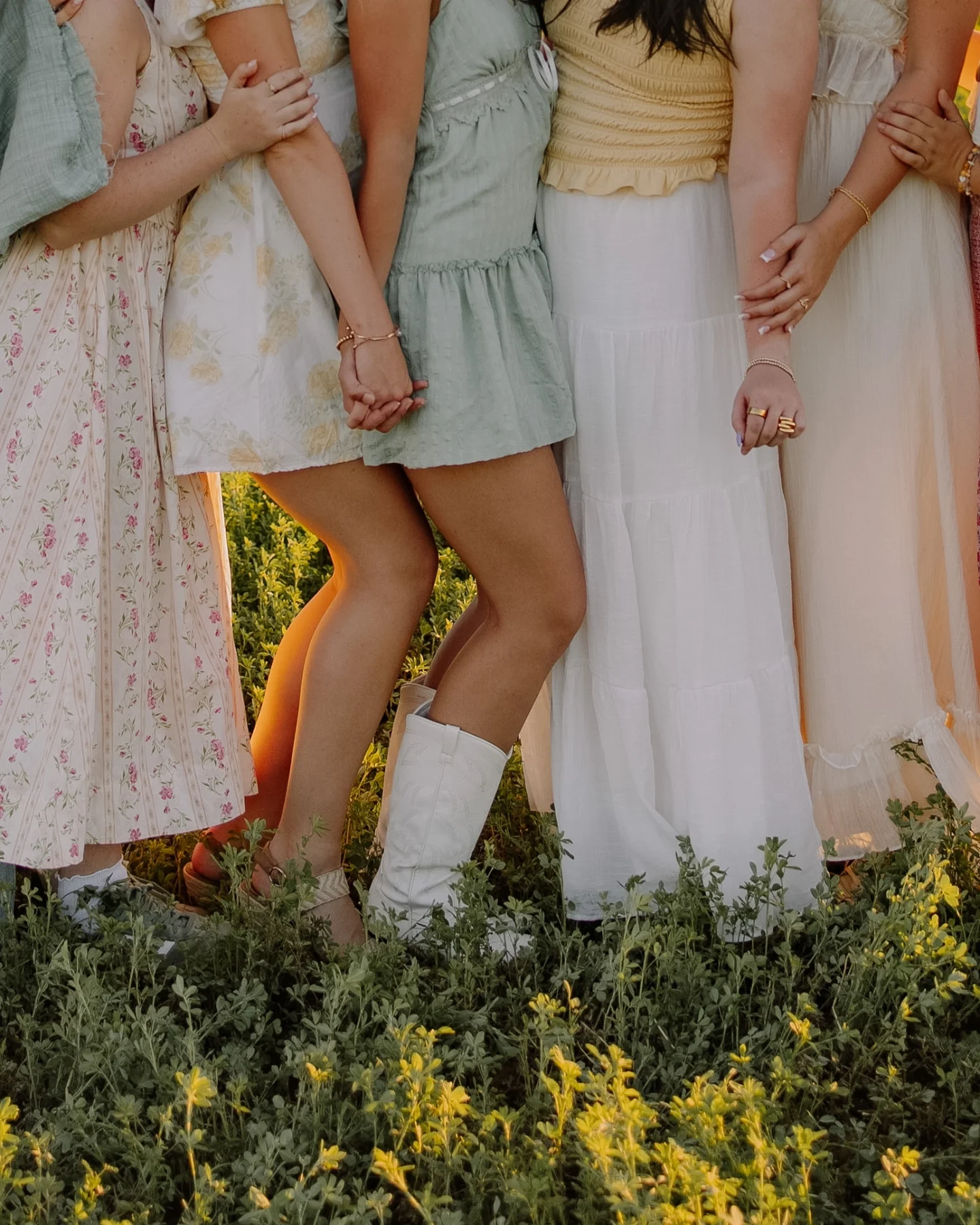 Women linking arms in a field of yellow flowers